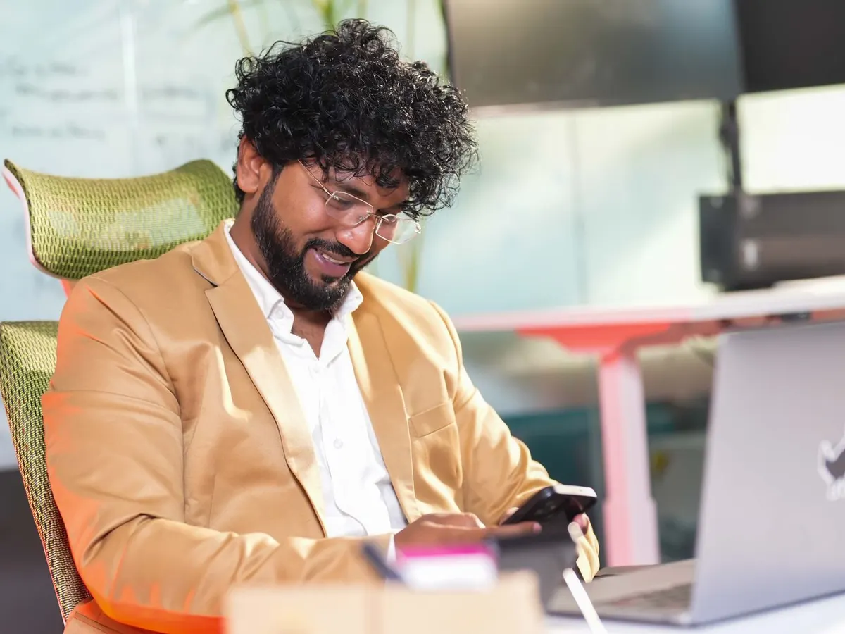 A business owner managing customer enquiries on a phone and laptop